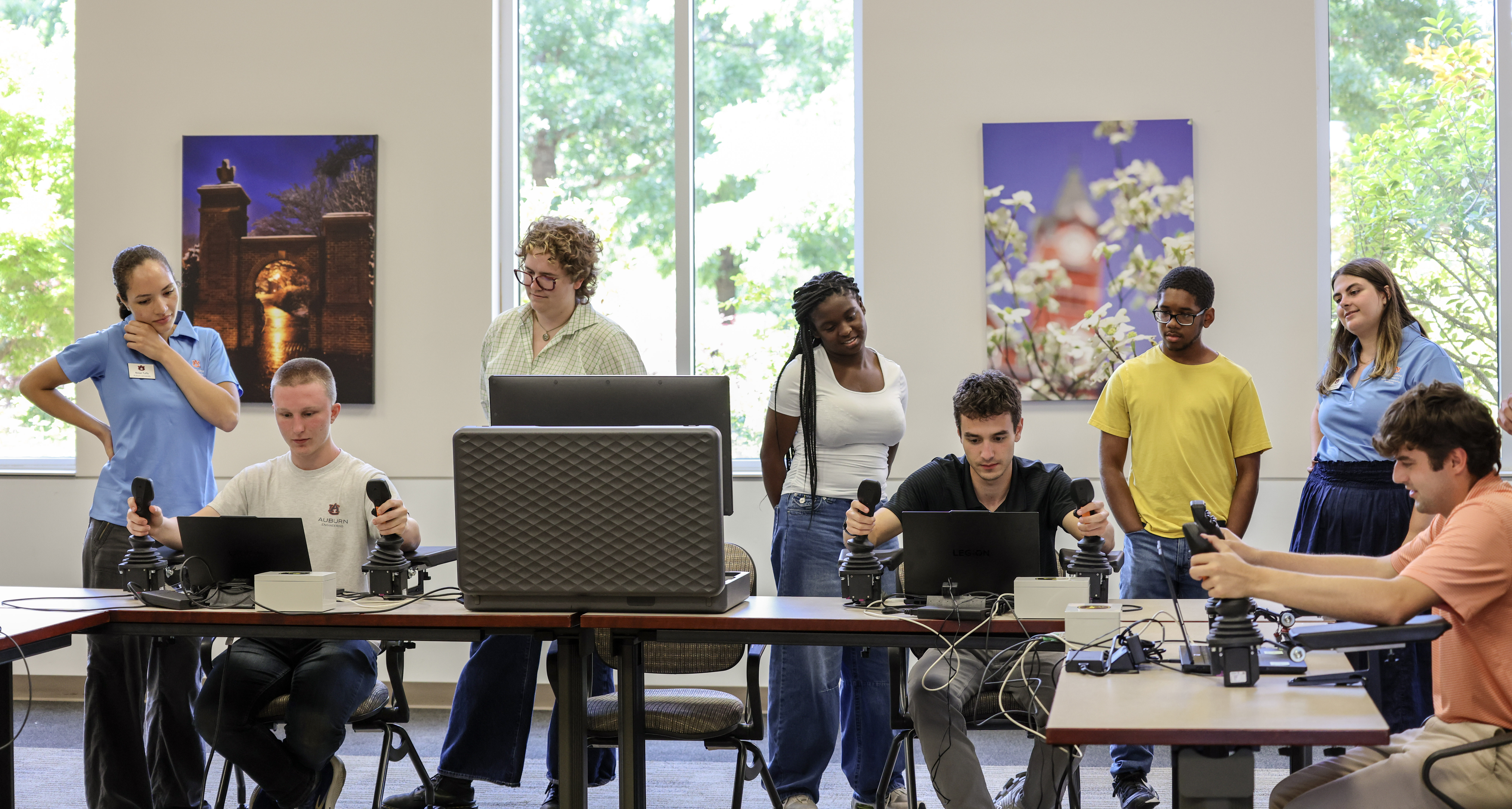 Group of students observing other students experimenting with agricultural computer hardware, indoors.